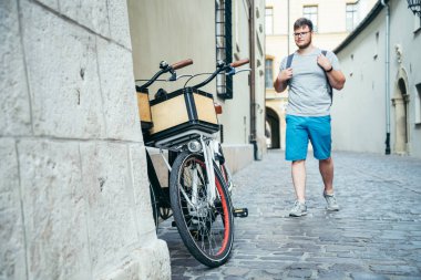 Eski Avrupa şehri sokak bisiklet tarafından yürüyen adam duvara yakın park