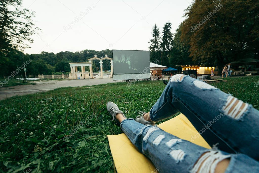 person lies on the ground and watch movie in open air cinema