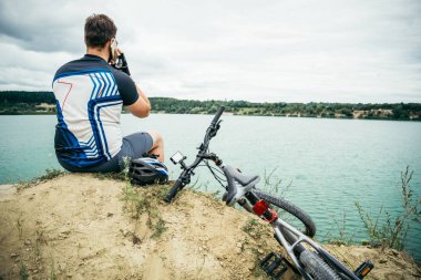 adam bisiklet ile tepenin zirvesine oturan ve görünümü resim çekmek