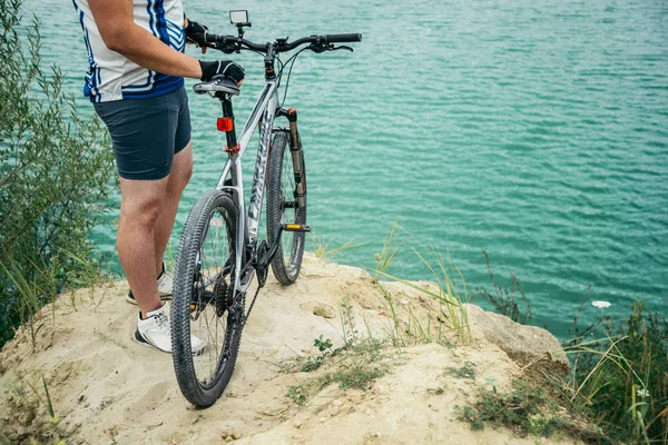 Man with bicycle stand on the hill and looking at the lake — Stock Photo, Image