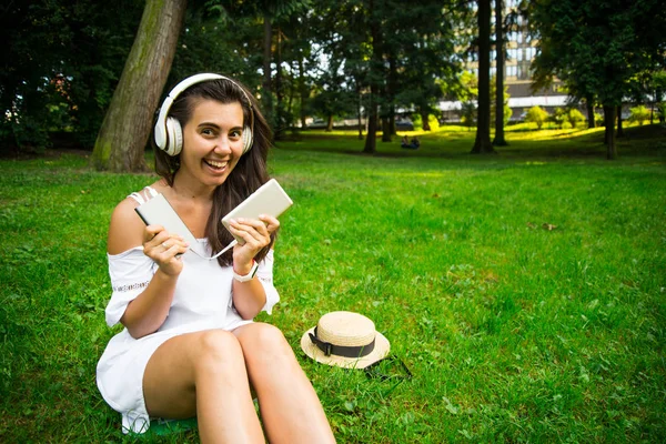 Woman in the park happy to use powerbank and continue listen music — Stock Photo, Image