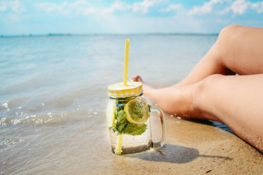 mojito kadın bacakları yakınındaki plajda bardak