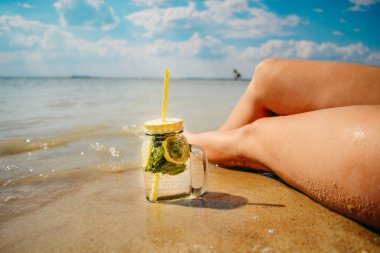 mojito kadın bacakları yakınındaki plajda bardak
