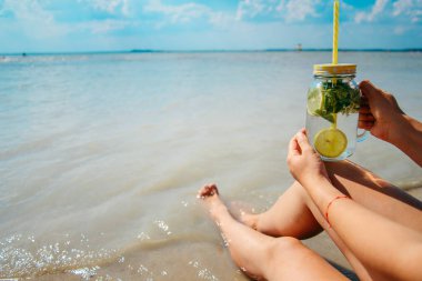 mojito kadın bacakları yakınındaki plajda bardak