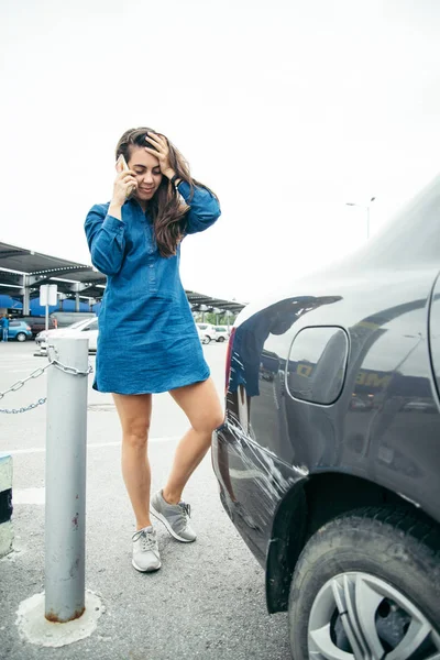 Sad woman standing near car with scratch — Stock Photo, Image