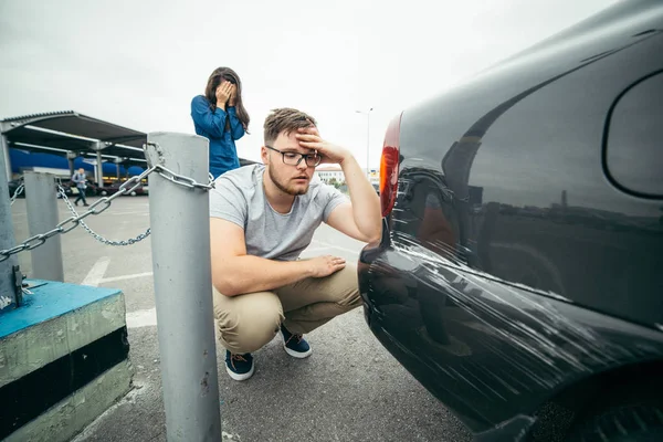 Sad man looking on car scratch, woman stand behind him — Stock Photo, Image