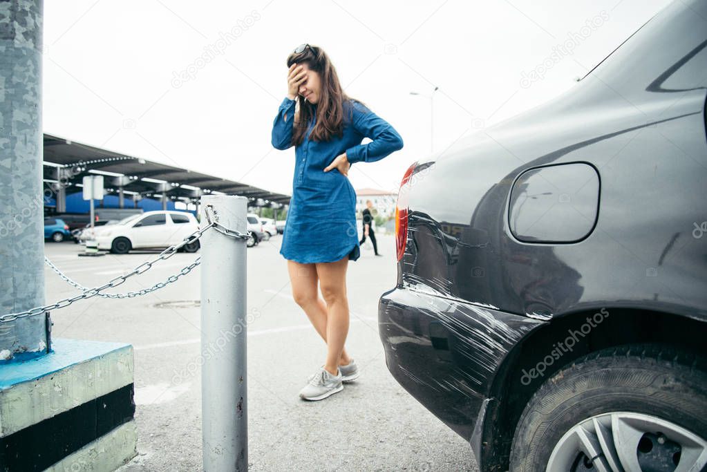 sad woman standing near car with scratch