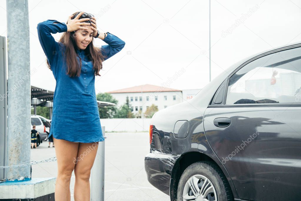 sad woman standing near car with scratch
