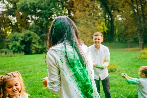 Linda familia europea trenzado con pinturas holi en el parque —  Fotos de Stock