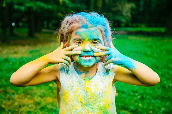 Retrato de niña feliz, toda la cara en pinturas holi — Foto de Stock