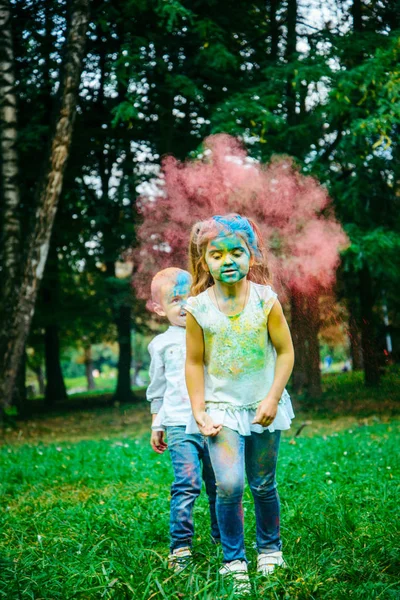 Niña con niño sentarse en el suelo todo sucio en pinturas holi —  Fotos de Stock