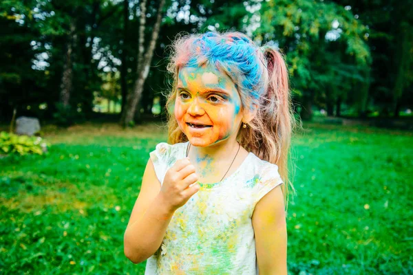 Retrato de niña feliz, toda la cara en pinturas holi — Foto de Stock