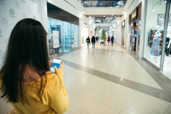 Woman walking by mall and check her phone — Stock Photo, Image