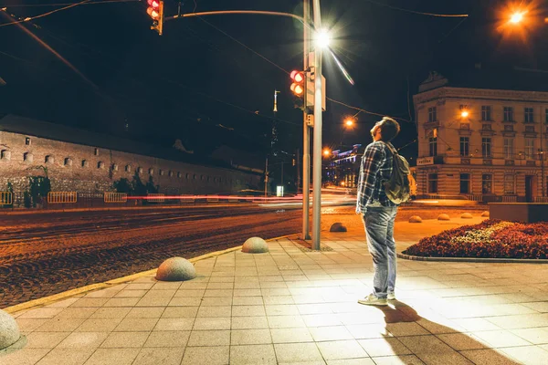 Homem de pé sob a luz no meio da cidade da noite — Fotografia de Stock