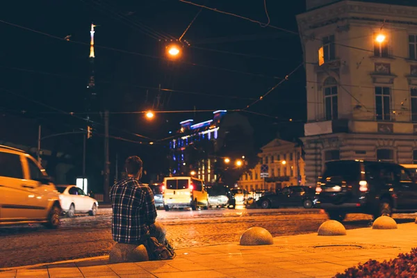 Homem sentado e olhando para a cidade da noite — Fotografia de Stock