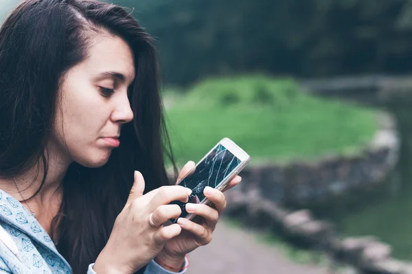 Woman sitting on the bench with cracked phone — Stock Photo, Image