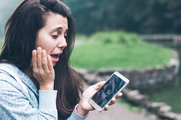 Nő ül a padon, repedt telefon — Stock Fotó