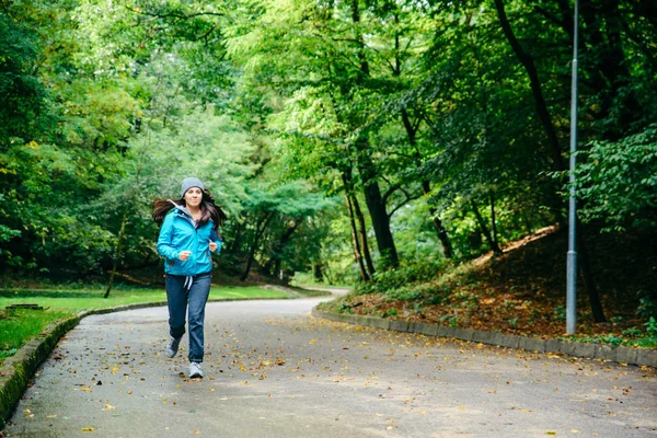 Молода красива жінка біжить потай в парку — стокове фото