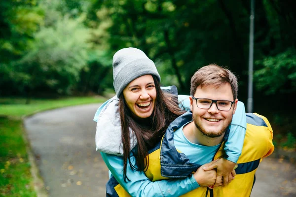 Çift spor giyim gülüyor, kadın atlamak adam omuzlarında