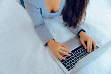 Tüylü halı üzerinde yalan ve dizüstü bilgisayarda çalışan kadın