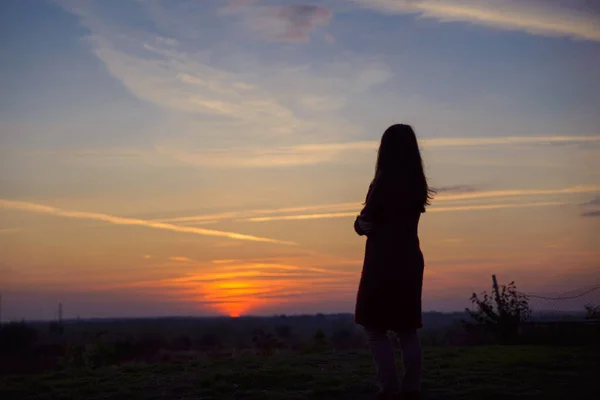 Силует молодої жінки, що стоїть на заході сонця — стокове фото