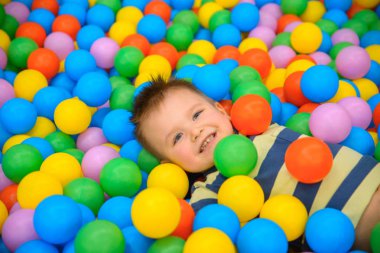 Birçok küçük renkli topları ile oyun odasında bir çocuk