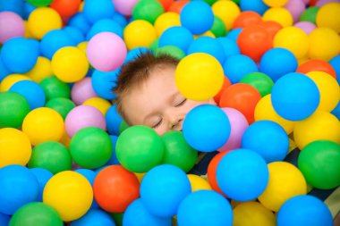 Birçok küçük renkli topları ile oyun odasında bir çocuk