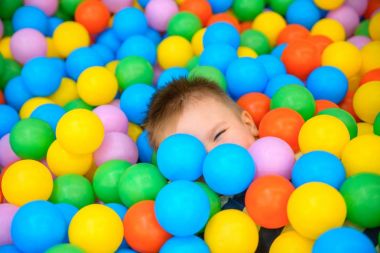 Birçok küçük renkli topları ile oyun odasında bir çocuk