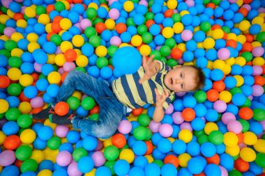 Birçok küçük renkli topları ile oyun odasında bir çocuk