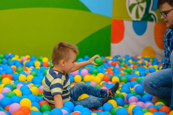 Bir çocuk babasına birçok küçük renkli topları ile oyun odasında