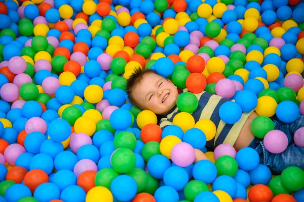 Un garçon dans la salle de jeux avec beaucoup de petites boules de couleur — Photo