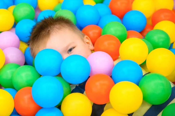 A boy in the playing room with many little colored balls — Stock Photo, Image
