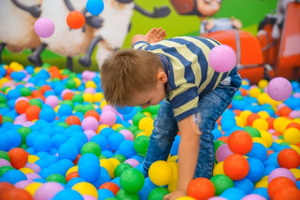 A fiú a játék szobában sok kis színes labdák — Stock Fotó