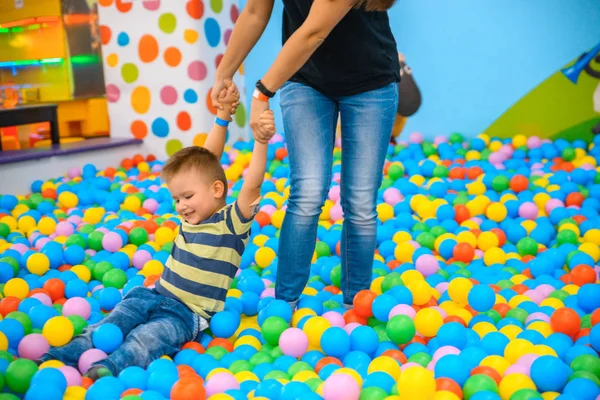 Un niño con madre en la sala de juegos con muchas pelotas de colores — Foto de Stock