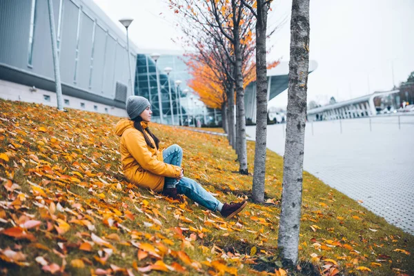 Жінка сидить на землі під жовтими деревами — стокове фото