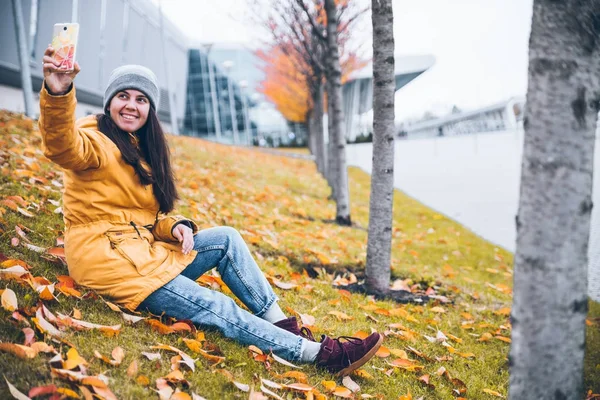 Woman sitting on the ground under yellow trees — Stock Photo, Image