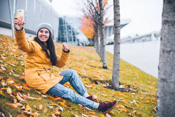 Woman sitting on the ground under yellow trees — Stock Photo, Image