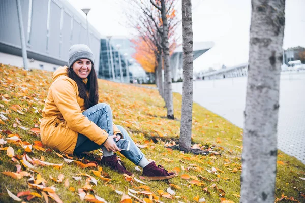 Vrouw zittend op de grond onder de gele bomen — Stockfoto