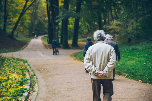 old man walking by autumn park