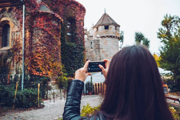 Молодая и счастливая туристка фотографирует старый замок — стоковое фото