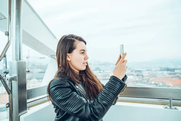 Beautiful girl taking picture at Ferris wheel on her phone — Stock Photo, Image
