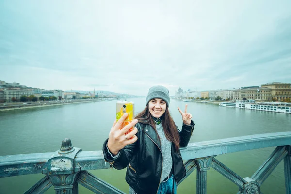 Jovem mulher tomando selfie na ponte um rio de cruz — Fotografia de Stock