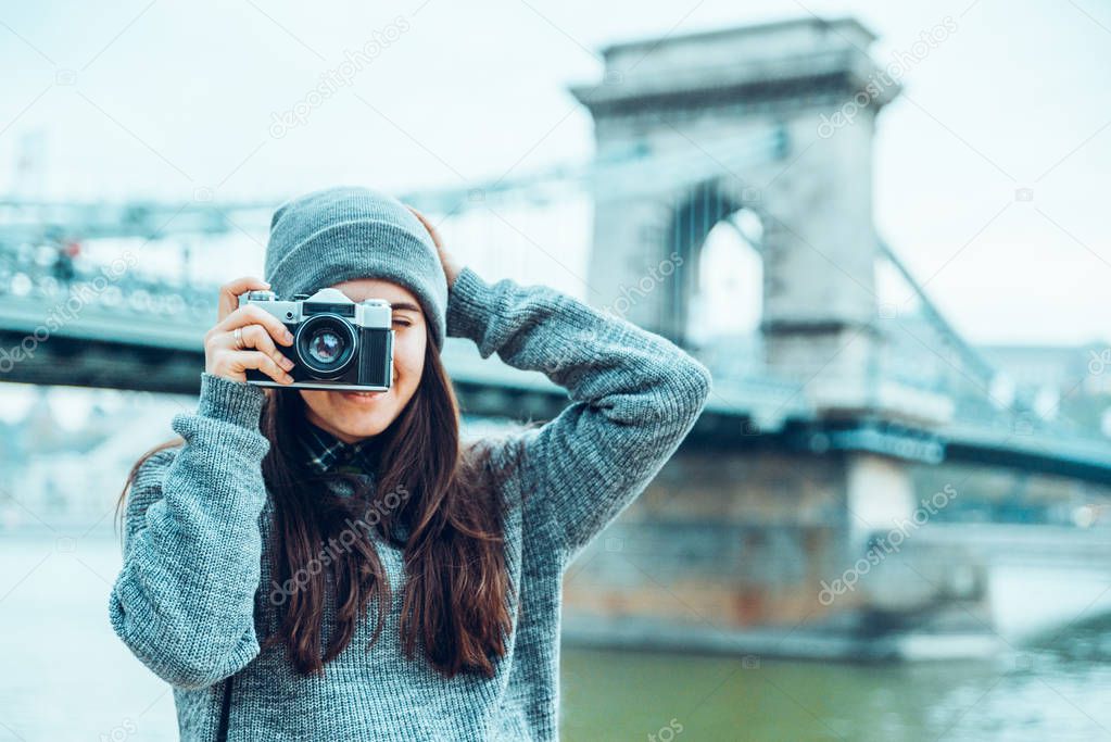 young pretty woman photographer shooting old bridge on background