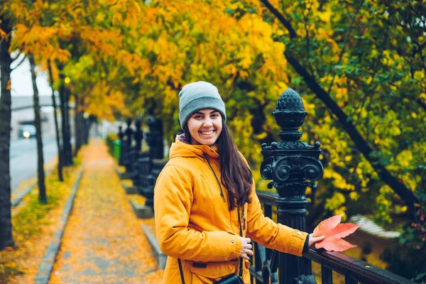 Vrouw lopen op een straat vol met gele bladeren in de herfst — Stockfoto