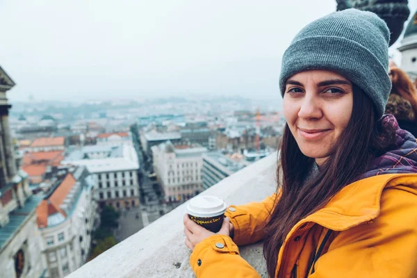 Donna con tazza di caffè guardando la città europea — Foto Stock