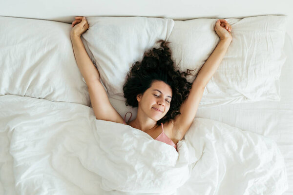 Молодая красивая женщина в постели с белыми простынями яркий свет
