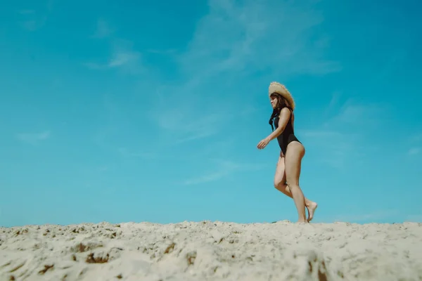 Mulher na praia de areia em preto maiô céu azul no fundo — Fotografia de Stock