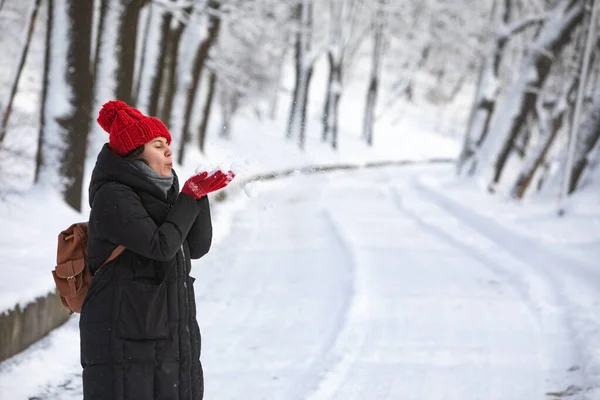 Jovem mulher sorridente bonita em casaco de inverno com chapéu vermelho no parque da floresta da cidade — Fotografia de Stock