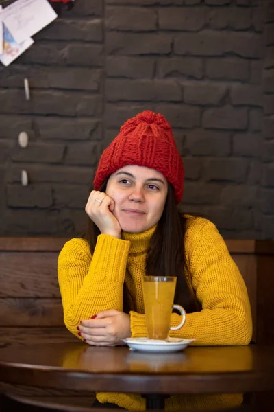 Young happy woman in red hat winter outfit sitting in cafe drinking warm up tea — Stock Photo, Image