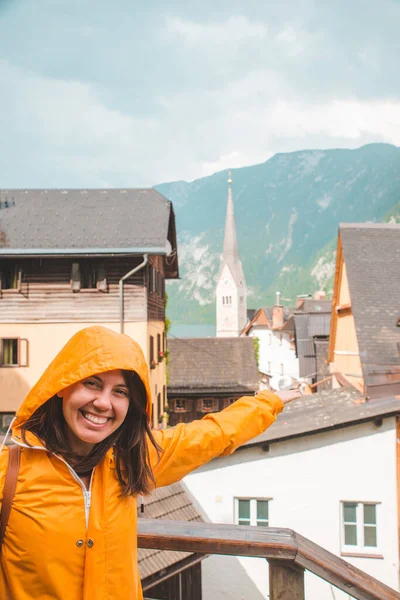 Portret van jonge lachende vrouw in gele regenjas in hallstatt stad — Stockfoto